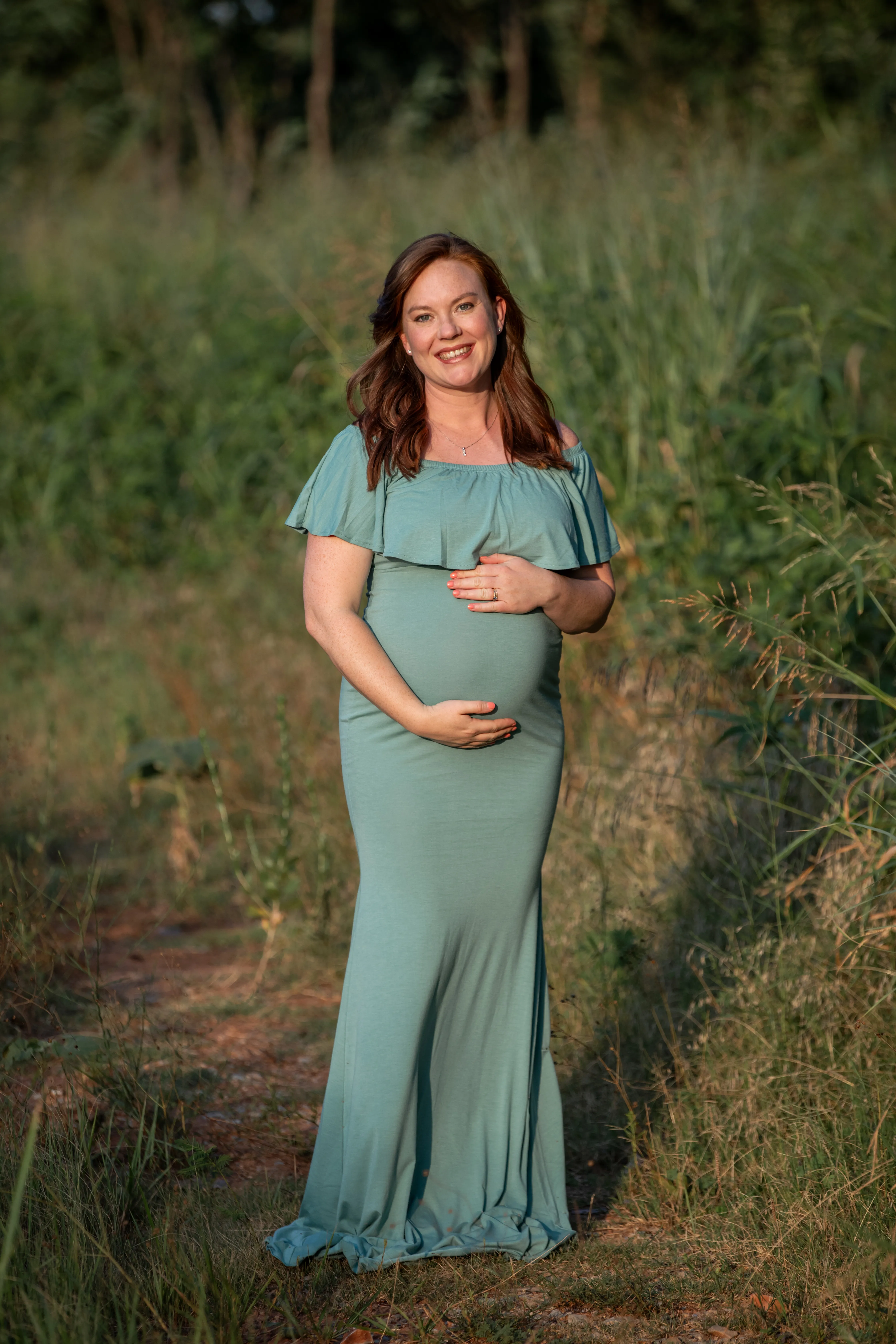 A pregnant woman in a dress in a field.